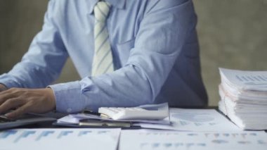 Genç Asyalı işadamı, defter, bütçe, vergi, finansal dökümanlar kullanırken gelir ve ev harcamalarını kaydediyor. Ev ekonomisi konsepti 4k 'de oturma odasında çalışmak.