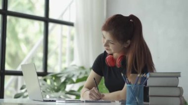 Bilgisayarlı kulaklık takan Asyalı kadın çevrimiçi eğitim konsepti şebekesinde kitap ve kitap