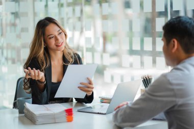 İki genç Asyalı iş ortağı organizasyonunun iş birliği konsepti: masa başında dizüstü bilgisayarla birlikte çalışan kadın ve erkek. Meslektaşlar şirketin mali durumunu tartışıyor.