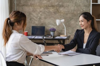 İş yeri fikri. Asyalı güzel bir kadın, ofis işi görüşmesi için İK müdürüyle konuşuyor. Çekici bir kadın masada oturuyor ve İnsan Kaynakları müdürüne resepsiyonda el sıkışarak iş özgeçmişi veriyor..