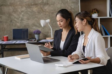 İki güzel Asyalı kadın, çevrimiçi iş için ekranlara bakan dizüstü bilgisayarları kullanarak birlikte çalışmanın yapısını tartışıyor. İnternet işbirliği kavramı