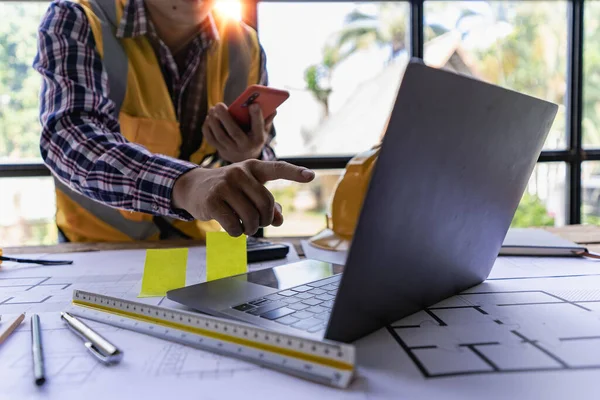 engineer working in office draw a construction project An architect\'s hand-drawn print engineer discusses floor plans over architectural blueprints at a desk in a modern office.