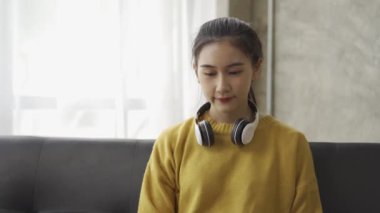 Asyalı üniversite öğrencileri evde kanepede dizüstü bilgisayarla ders çalışıyor.