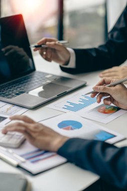 İş ekibi hesap makineleri ve iş grafikleri üzerinde çalışıyor. Finansal muhasebeci asistanı. Satış müdürü ya da pazarlamacı. Resmi kıyafet dikey resmi.