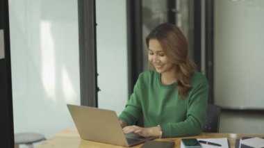İnternette dizüstü bilgisayarı olan bir kafede çalışan Asyalı kadın.