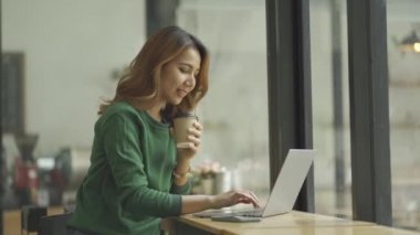 İnternette dizüstü bilgisayarı olan bir kafede çalışan Asyalı kadın.
