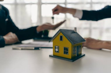 Emlakçılar ve satış temsilcileri yeni evlerden ofis müşterilerine ev örnekleri dağıtırlar..