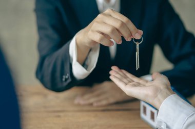 Emlakçılar ve satış temsilcileri yeni evlerden ofis müşterilerine ev örnekleri dağıtırlar..