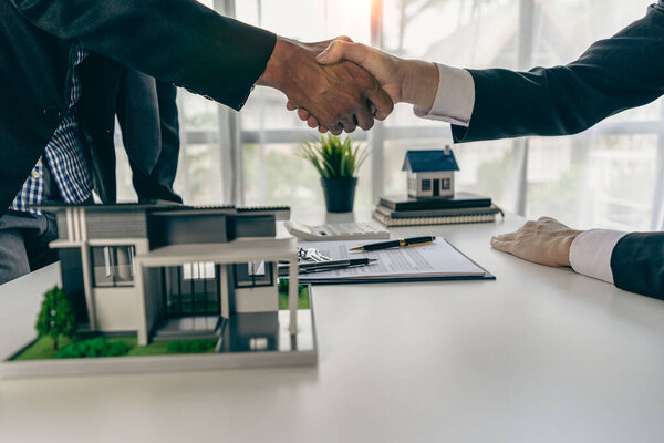 Представители по продажам пожимают руку клиентам и предлагают контракты на покупку жилья для приобретения действующих домов и аренды предлагают проекты домовладельцев при подписании договора со страховой компанией.