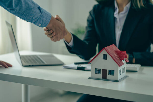 Sales representatives shake hands with customers and offer home purchase contracts to purchase current homes and leases offer homeowners projects upon signing of contract with insurance.