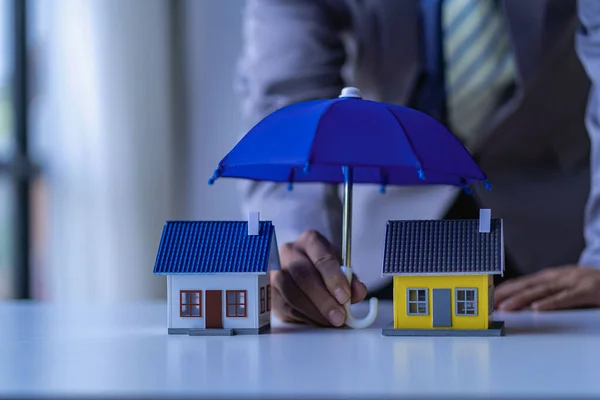 Home and real estate insurance ideas, individuals holding small umbrellas and sample homes. Home insurance for upcoming losses and fires building fire insurance