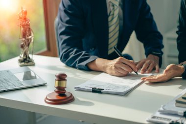 İşadamı ve avukat kontrat belgelerini altın pullarla tartışıyor, adalet tanrısı, hukuk bürosundaki ahşap masa üzerinde sarı, tavsiye, adalet kavramı