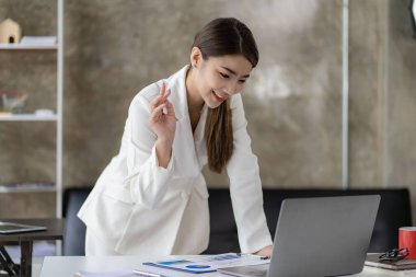 Modern ofiste dizüstü bilgisayarda çalışan gülümseyen Asyalı iş kadını, muhasebeci, konsept, finans, uzman, analiz, iş raporu, grafik, finans şeması, ekonomi, şirket, bankacılık, piyasa araştırması.