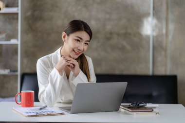Modern ofiste dizüstü bilgisayarda çalışan gülümseyen Asyalı iş kadını, muhasebeci, konsept, finans, uzman, analiz, iş raporu, grafik, finans şeması, ekonomi, şirket, bankacılık, piyasa araştırması.