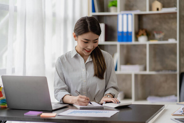 Smiling Asian businesswoman working on laptop in modern office, accountant, concept, finance, expert, analysis, business report, graph, financial chart, economy, corporate, banking, market research.