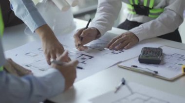 İnşaat inşaatçıları, mimarlar, mühendisler ve müfettişlerle inşaat toplantıları. Ofisteki çeşitli planlama planlarına bakıyorlardı. 4K stok video klibi.