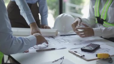 İnşaat inşaatçıları, mimarlar, mühendisler ve müfettişlerle inşaat toplantıları. Ofisteki çeşitli planlama planlarına bakıyorlardı. 4K stok video klibi.