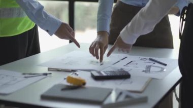 İnşaat inşaatçıları, mimarlar, mühendisler ve müfettişlerle inşaat toplantıları. Ofisteki çeşitli planlama planlarına bakıyorlardı. 4K stok video klibi.