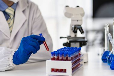 Bilimadamları laboratuvar tıbbi konseptinde üzerinde kan olan bir test tüpünü tutuyorlar.