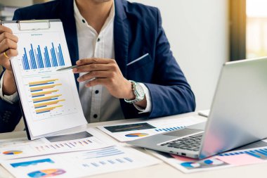 Elinde kalem tutan işadamı, mali kağıt grafiğini analiz ederken grafiğe işaret ediyor.