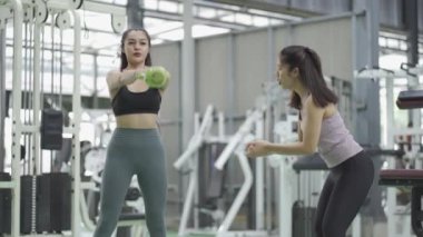 Spor salonunda çalışan, siyah elbiseli ve taytlı iki seksi Asyalı kız. Spor ve spor eğitimi yapmak Sağlıklı yaşam tarzı.