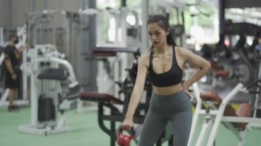 Kız spor salonunda spor yapıyor ve spor yapıyor. Seksi fitness kızı. Uzun siyah saçlı güzel bir kız.