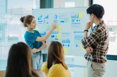 Asyalı yaratıcı takımlar bir atölyede ilham verici yaratıcılığı paylaşmak için birlikte oturup çalışırlar. Genç modern iş adamları iş yerinde grafik kağıdı ve dizüstü bilgisayarla buluşuyorlar..