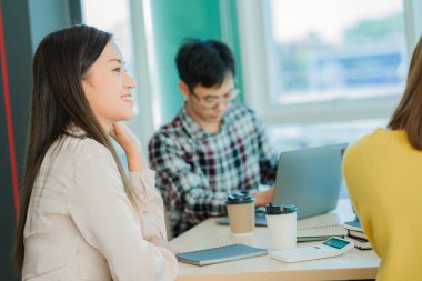 Asyalı yaratıcı takımlar bir atölyede ilham verici yaratıcılığı paylaşmak için birlikte oturup çalışırlar. Genç modern iş adamları iş yerinde grafik kağıdı ve dizüstü bilgisayarla buluşuyorlar..