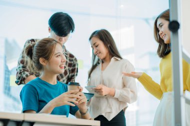 Asyalı yaratıcı takımlar bir atölyede ilham verici yaratıcılığı paylaşmak için birlikte oturup çalışırlar. Genç modern iş adamları iş yerinde grafik kağıdı ve dizüstü bilgisayarla buluşuyorlar..