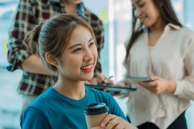 Asyalı yaratıcı takımlar bir atölyede ilham verici yaratıcılığı paylaşmak için birlikte oturup çalışırlar. Genç modern iş adamları iş yerinde grafik kağıdı ve dizüstü bilgisayarla buluşuyorlar..