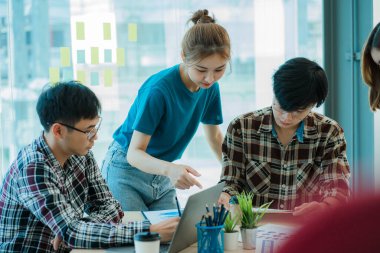 Asyalı yaratıcı takımlar bir atölyede ilham verici yaratıcılığı paylaşmak için birlikte oturup çalışırlar. Genç modern iş adamları iş yerinde grafik kağıdı ve dizüstü bilgisayarla buluşuyorlar..