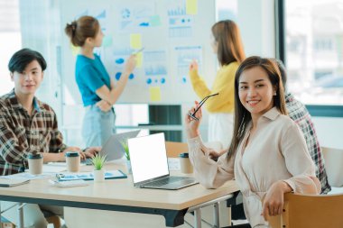 Asyalı yaratıcı takımlar bir atölyede ilham verici yaratıcılığı paylaşmak için birlikte oturup çalışırlar. Genç modern iş adamları iş yerinde grafik kağıdı ve dizüstü bilgisayarla buluşuyorlar..