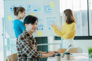 Asyalı yaratıcı takımlar bir atölyede ilham verici yaratıcılığı paylaşmak için birlikte oturup çalışırlar. Genç modern iş adamları iş yerinde grafik kağıdı ve dizüstü bilgisayarla buluşuyorlar..