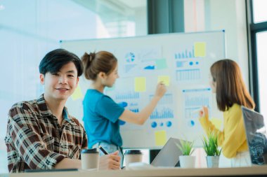 Asyalı yaratıcı takımlar bir atölyede ilham verici yaratıcılığı paylaşmak için birlikte oturup çalışırlar. Genç modern iş adamları iş yerinde grafik kağıdı ve dizüstü bilgisayarla buluşuyorlar..