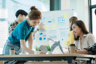 Asyalı yaratıcı takımlar bir atölyede ilham verici yaratıcılığı paylaşmak için birlikte oturup çalışırlar. Genç modern iş adamları iş yerinde grafik kağıdı ve dizüstü bilgisayarla buluşuyorlar..