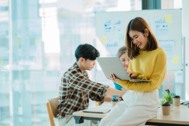 Asyalı yaratıcı takımlar bir atölyede ilham verici yaratıcılığı paylaşmak için birlikte oturup çalışırlar. Genç modern iş adamları iş yerinde grafik kağıdı ve dizüstü bilgisayarla buluşuyorlar..