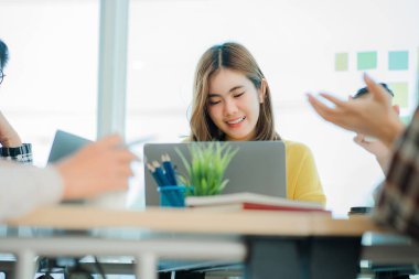 Asyalı yaratıcı takımlar bir atölyede ilham verici yaratıcılığı paylaşmak için birlikte oturup çalışırlar. Genç modern iş adamları iş yerinde grafik kağıdı ve dizüstü bilgisayarla buluşuyorlar..