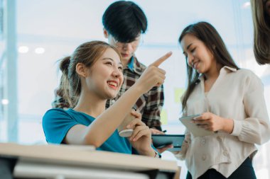 Asyalı yaratıcı takımlar bir atölyede ilham verici yaratıcılığı paylaşmak için birlikte oturup çalışırlar. Genç modern iş adamları iş yerinde grafik kağıdı ve dizüstü bilgisayarla buluşuyorlar..