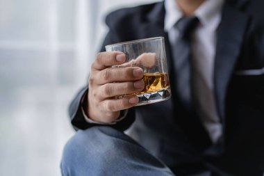 Barmen erkek konuğa bir bardak viski ve buz tutuyor. Bardaki konseptin geri kalanı elinde viski olan ciddi bir iş adamının yakın planda yürütme ayrıcalığı kavramını gösteriyor..