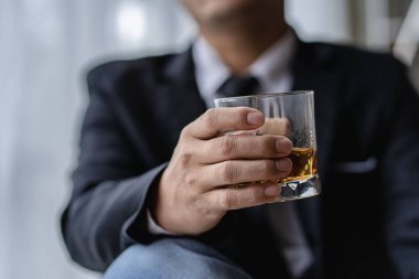 Barmen erkek konuğa bir bardak viski ve buz tutuyor. Bardaki konseptin geri kalanı elinde viski olan ciddi bir iş adamının yakın planda yürütme ayrıcalığı kavramını gösteriyor..