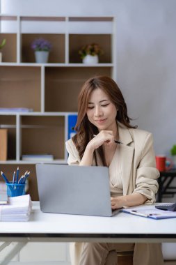 Ofiste dizüstü bilgisayar kullanan Asyalı bir kadın muhasebe analizi hazırlıyor emlak yatırım bilgileri vergi bilgileri ve finansal sistemler dikey resim