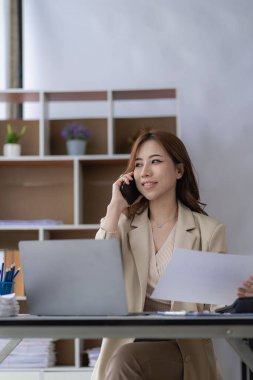 Ofiste dizüstü bilgisayar kullanan Asyalı bir kadın muhasebe analizi hazırlıyor emlak yatırım bilgileri vergi bilgileri ve finansal sistemler dikey resim