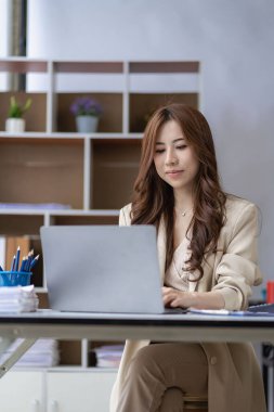 Ofiste dizüstü bilgisayar kullanan Asyalı bir kadın muhasebe analizi hazırlıyor emlak yatırım bilgileri vergi bilgileri ve finansal sistemler dikey resim