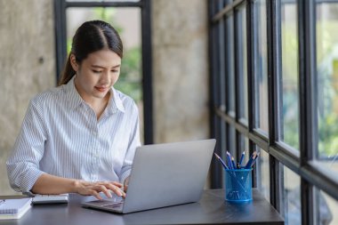 Laptop işi fikriyle bir kafede çalışan Asyalı mutlu bir kız.