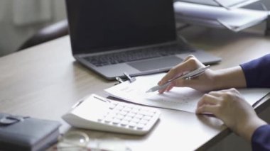 Genç Asyalı iş kadını, gelir vergisi ve kurumsal geliri özel ofiste hesaplamak için hesap makinesine baskı yapıyor. Maliye, muhasebe, pazarlamacının istatistiksel grafiği.