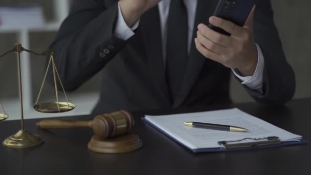 オンライン弁護士概念裁判官のハンマーとスケール背景にスマートフォンのメッセージに答える弁護士の横に配置 — ストック動画