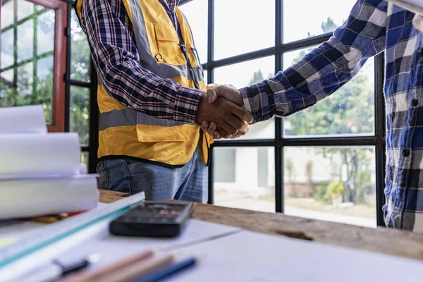 Architects and construction workers shake hands while working as a team and collaborative concept after completing an agreement on a construction site.