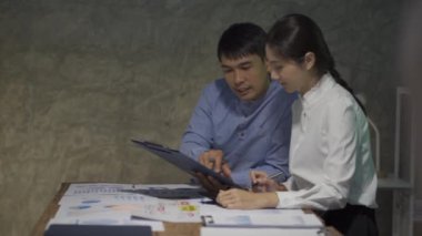 Asyalı iş ekibiyle tanışın, tartışın, beyin fırtınası yapın ve muhasebe konferans odasında dizüstü bilgisayarlarda ve tabletlerde aylık pazarlama raporlarını tartışın. 4K UHD Fazla Mesai Kavramı