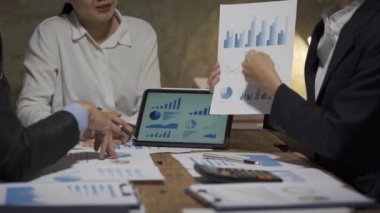 Asyalı iş ekibiyle tanışın, tartışın, beyin fırtınası yapın ve muhasebe konferans odasında dizüstü bilgisayarlarda ve tabletlerde aylık pazarlama raporlarını tartışın. 4K UHD Fazla Mesai Kavramı