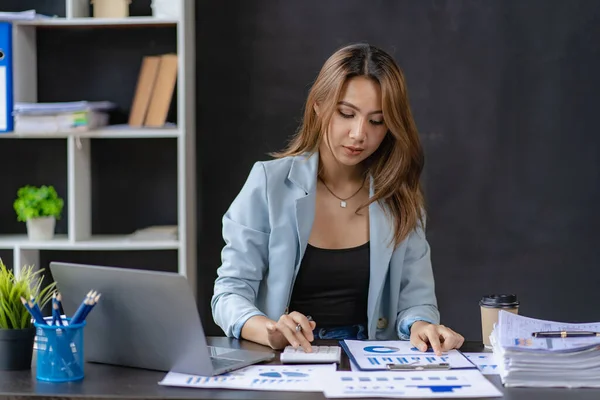 Business woman using calculator for math finance on wooden table and business background, tax, accounting, statistics and analytical research concepts in office.